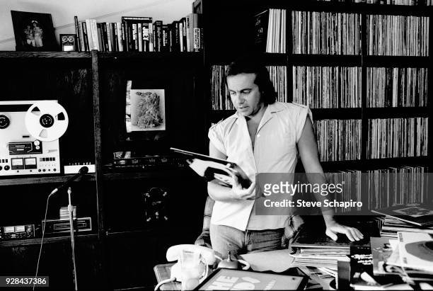View of British musician and lyricist Bernie Taupin as he looks at a record in his home office, Los Angeles, California, April 1980.