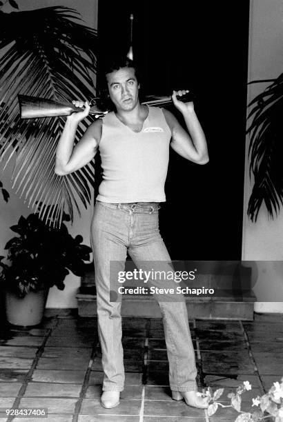 Portrait of British musician and lyricist Bernie Taupin as he poses with a shotgun over his shoulders, Los Angeles, California, April 1980.