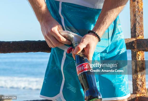 Dylan Haerle opens a Coke-Cola bottle with the Boardshort Bottle Opener made by Island Daze at The Artists Project Give Back Day on February 28, 2018...
