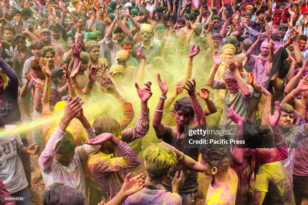 Coloured powder is thrown on men as they dance during Holi...