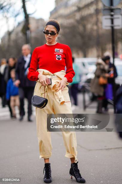 Lena Perminova wears sunglasses, a red pull over, cropped pants, balck shoes, outside Miu Miu, during Paris Fashion Week Womenswear Fall/Winter...