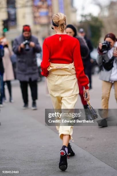 Lena Perminova wears sunglasses, a red pull over, cropped pants, balck shoes, outside Miu Miu, during Paris Fashion Week Womenswear Fall/Winter...