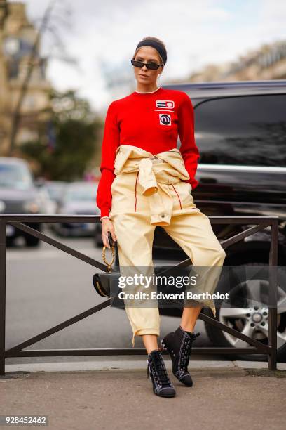 Lena Perminova wears sunglasses, a red pull over, cropped pants, balck shoes, outside Miu Miu, during Paris Fashion Week Womenswear Fall/Winter...