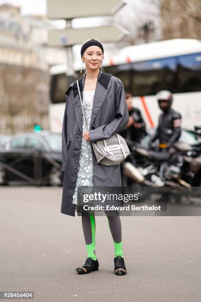 Irene Kim wears a bandanna, a gray coat, a lace dress, a gray bag, leggings, outside Miu Miu, during Paris Fashion Week Womenswear Fall/Winter...