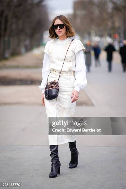 Candela Novembre wears a white dress, sunglasses, a Chanel bag, black boots, outside Chanel, during Paris Fashion Week Womenswear Fall/Winter...