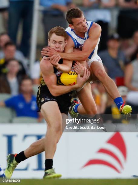 Kayne Turner of the Kangaroos and Jacob Townsend of the Tigers collide as they compete for the ball in the 2nd quarter during the AFL JLT Community...