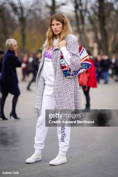 Veronika Heilbrunner wears a tweed coat, a Chanel bag, white pants, white sneakers, outside Chanel, during Paris Fashion Week Womenswear Fall/Winter...