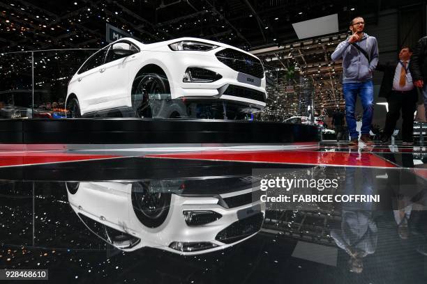 Visitors walk past a Ford Edge car during the second press day of the Geneva International Motor Show, on March 7, 2018 in Geneva. The show opens to...