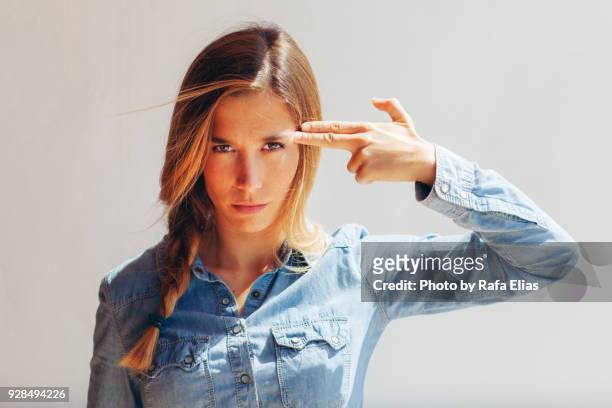 pretty woman pointing her finger to her head - western shirt stockfoto's en -beelden
