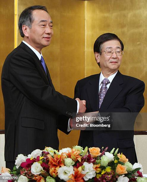 Hitoshi Tsunekage, president of Sumitomo Trust & Banking Co., left, and Kazuo Tanabe, president of Chuo Mitsui Trust Holding Inc., shake hands during...