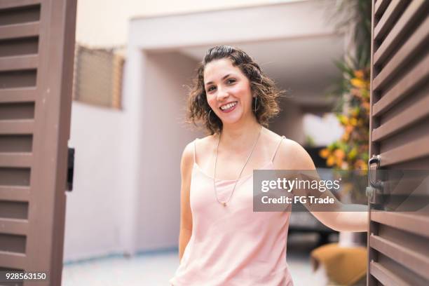 woman opening her front door - door greeting stock pictures, royalty-free photos & images