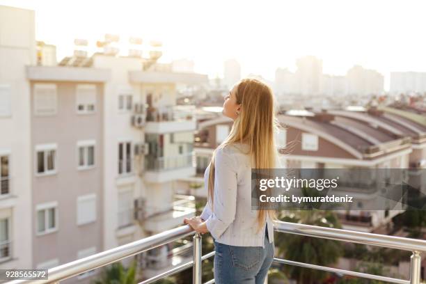 woman standing and relaxing on balcony - bad part of town stock pictures, royalty-free photos & images