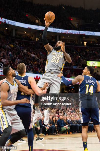 Nikola Jokic and Gary Harris of the Denver Nuggets guard LeBron James of the Cleveland Cavaliers as he shoots during the second half at Quicken Loans...