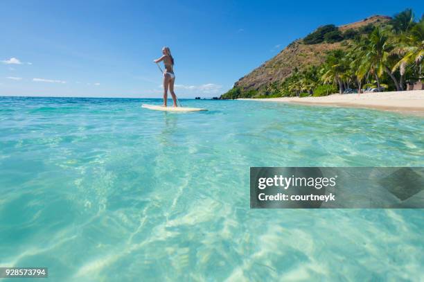 woman paddling on a stand up paddleboard. - fiji people stock pictures, royalty-free photos & images