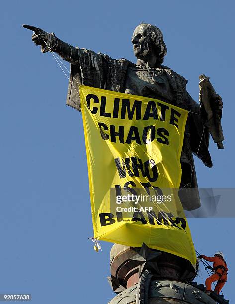 Activists of the environmental group Greenpeace hang a banner reading "Climate Chaos, Who is to Blame?" from the Cristobal Colon statue on November...