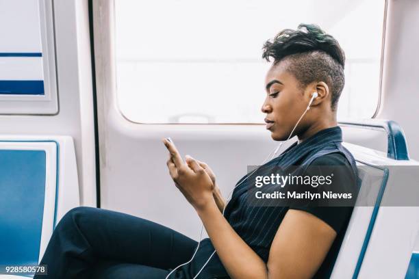 hip black businesswoman texting while sitting in the train - mohawk stock pictures, royalty-free photos & images