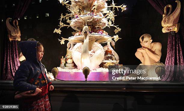 Small child watches as ballet dancers from Sadler's Wells Theatre pose in the newly unveiled Christmas window of Fortnum & Mason grocery store on...