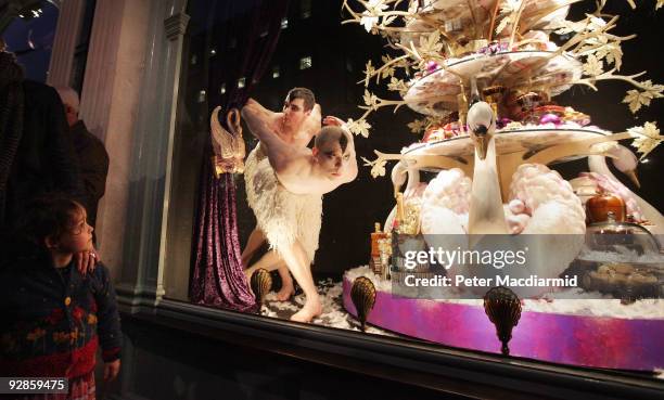 Small child watches as ballet dancers from Sadler's Wells Theatre pose in the newly unveiled Christmas window of Fortnum & Mason grocery store on...