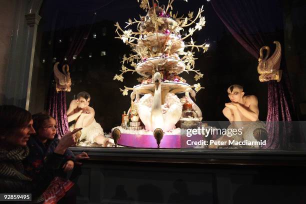 Small child and her mother watch as ballet dancers from Sadler's Wells Theatre pose in the newly unveiled Christmas window of Fortnum & Mason grocery...