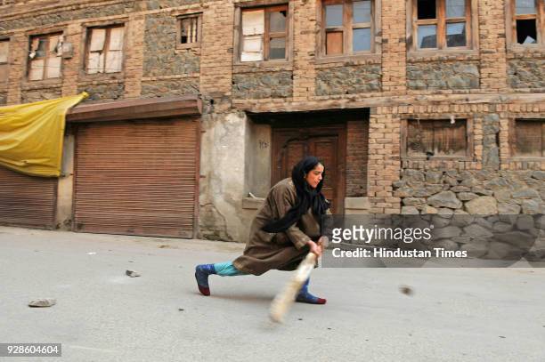 Girl plays cricket on the street during restriction on March 7, 2018 in downtown area of Srinagar, India. Authorities today imposed restrictions in...