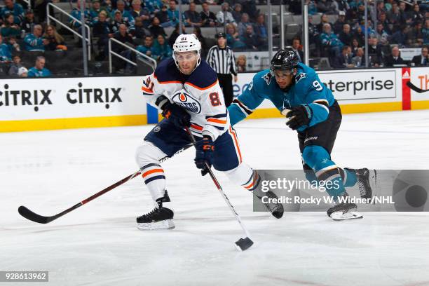 Yohann Auvitu of the Edmonton Oilers skates with the puck against Evander Kane of the San Jose Sharks at SAP Center on February 27, 2018 in San Jose,...