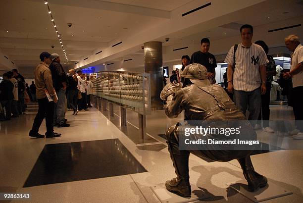 Fans look at the collection of autographed baseballs mounted within the case that stands under the arc of the path of the final pitch to catcher Yogi...