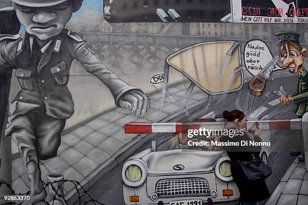 Visitor takes a snapshot along a still-existing portion of the former Berlin Wall known as the East Side Gallery on its official re-opening day on...