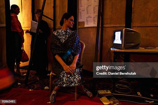 Pakistani model Nadia Ali, wearing a creation by Pakistani designer Mahin Hussain watches a television displaying the show backstage during the 3rd...