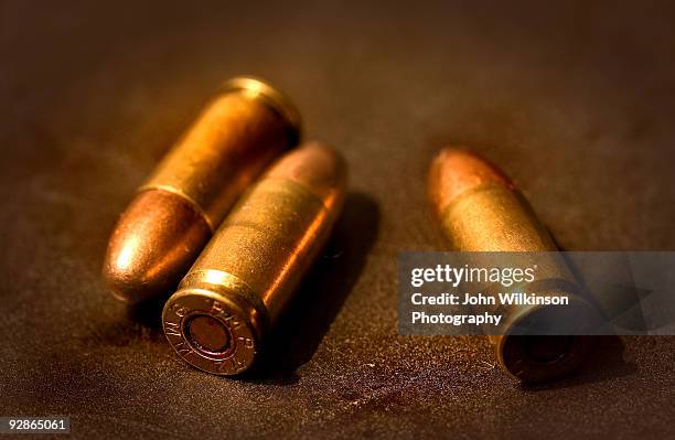 three bullets on textured background - bala munición fotografías e imágenes de stock