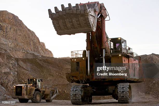 Hitachi excavator , right, and Caterpillar wheel loader are used at the AngloGold Ashanti Ltd. Cripple Creek & Victor gold mine in Victor/Cripple...
