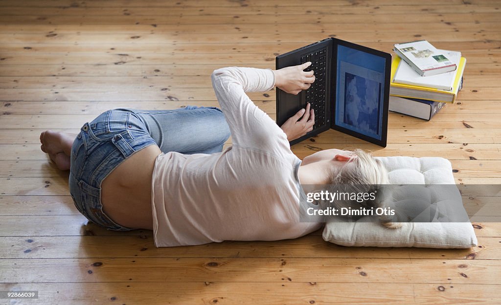 Woman lying in her side typing on a laptop 