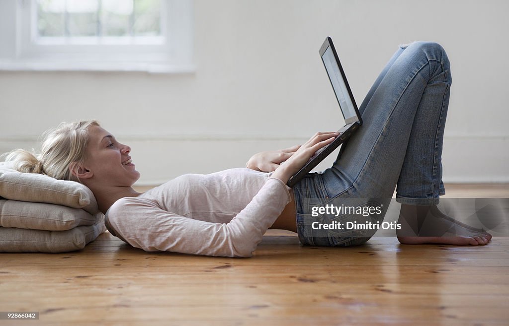 Woman lying on floor working on her laptop