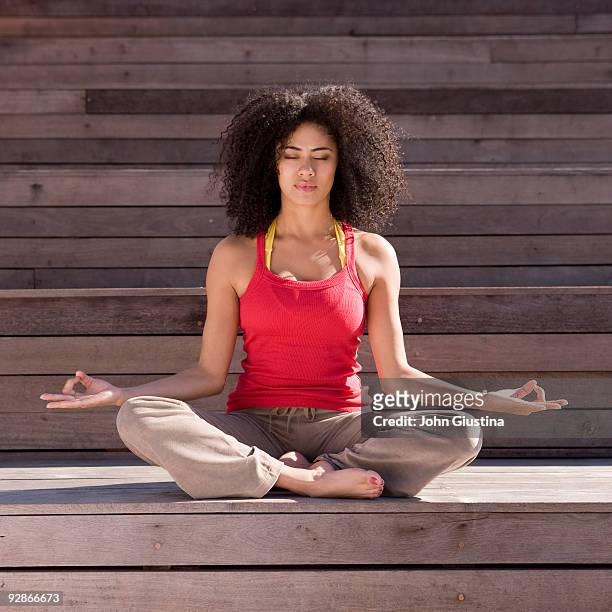 woman meditating outside with her eyes closed. - schneidersitz stock-fotos und bilder