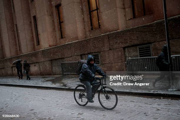 Man rides a bicycle in the Financial District during a snowstorm March 7, 2018 in New York City. This is the second nor'easter to hit the area within...