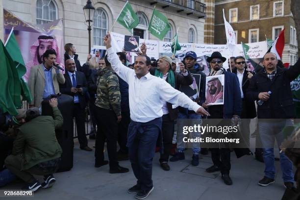 Supporters and Saudi nationals hold flags and photos of Mohammed bin Salman, Saudi Arabia's crown prince, during a visit with Theresa May, U.K. Prime...