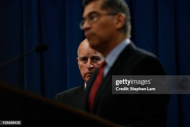 California Governor Jerry Brown looks on as Attorney General Xavier Becerra speaks during a press conference at the California State Capitol on March...