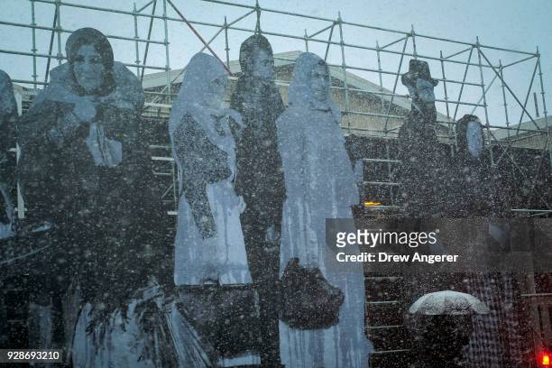 An art installation by French artist JR features refugees on the facade of Pier 94 during a snowstorm, March 7, 2018 in New York City. This is the...