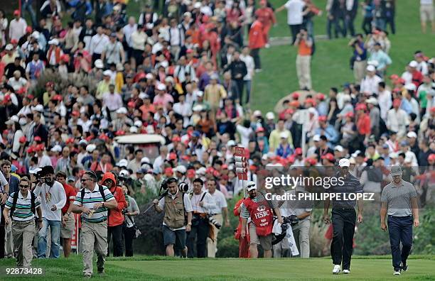 Crowd follows US golfer Tiger Woods as he walks side by side with compatriot Ryan Moore during the HSBC Champions golf tournament in Shanghai on...