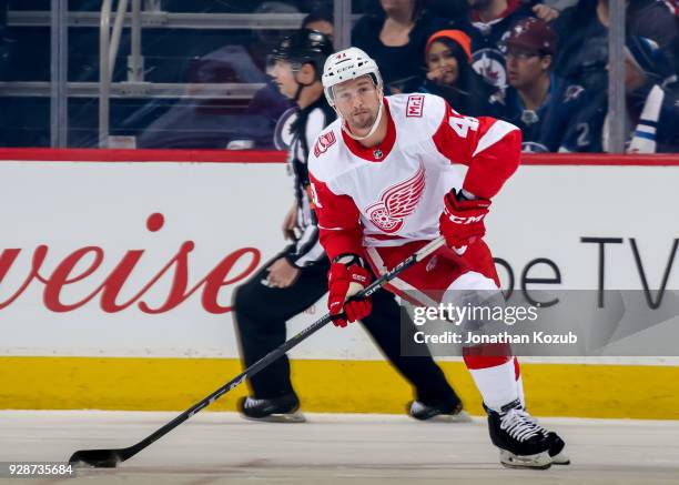 Luke Glendening of the Detroit Red Wings plays the puck up the ice during first period action against the Winnipeg Jets at the Bell MTS Place on...