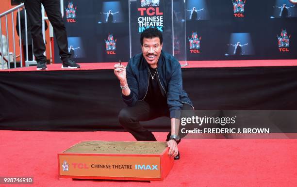 Lionel Ritchie poses after siging his name in the block of cement at his Hand and Footprints ceremony at the TCL Theater on March 7,2018 in...