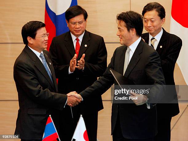 Laotian Foreign Minister Thongloun Sisoulith, left, shakes hands with his Japanese counterpart Katuya Okada, 2nd right, as Laotian Prime Minister...
