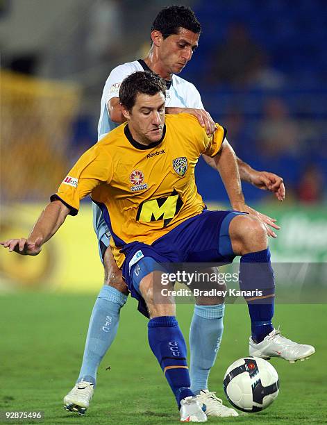 Joel Porter of the Gold Coast is challenged by Simon Colosimo of Sydney during the round 14 A-League match between Gold Coast United and Sydney FC at...