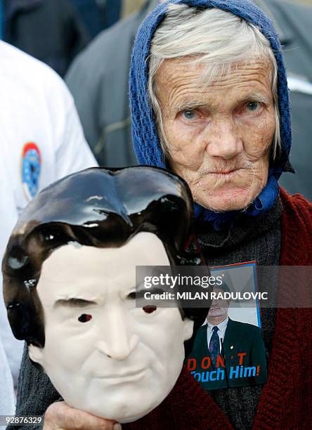 Bosnian Serb shows a mask featuring the face of Bosnian Serb wartime leader Radovan Karadzic during a protest organized to show support of Bosnian...