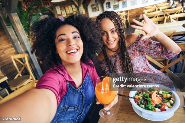 young women in restaurant drinking juice and eating salad - woman drinking juice stock pictures, royalty-free photos & images