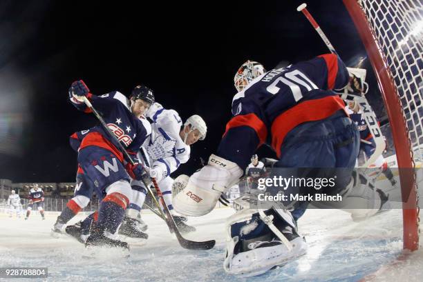 Leo Komarov of the Toronto Maple Leafs and Christian Djoos of the Washington Capitals battle for the puck in front of goaltender Braden Holtby during...