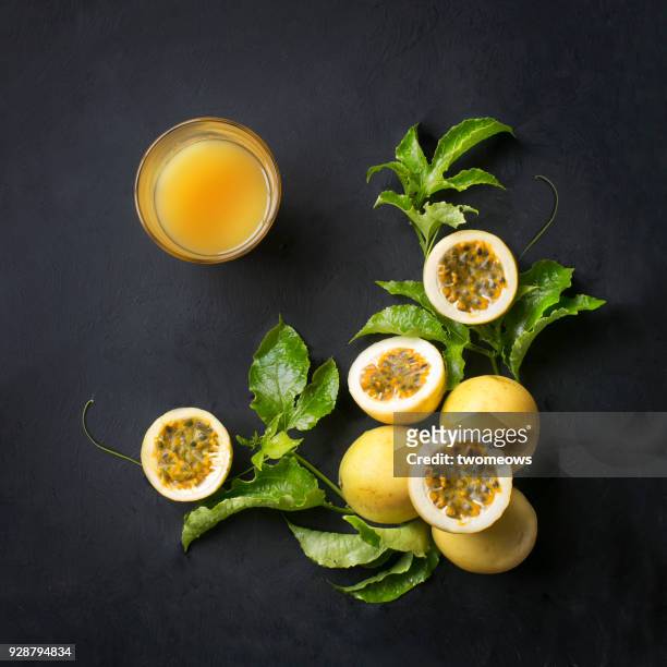 overhead view of yellow skin passion fruit and juice on black background. - passionfruit stock pictures, royalty-free photos & images