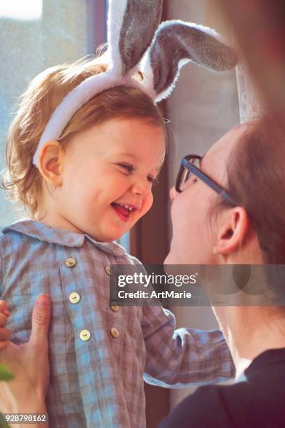 bebé con orejas de conejo y su madre en semana santa - easter family fotografías e imágenes de stock