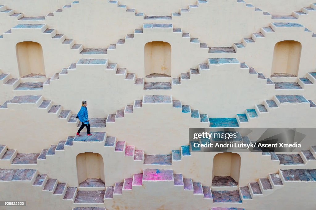 Young woman climbs staircase maze