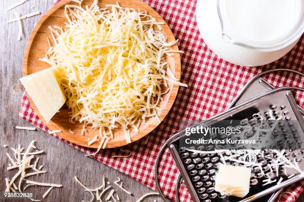 ingredients for pasta dish or pizza - milk, freshly grated parmesan cheese on a wooden table, and kitchen utensils (grater) on a wooden table, top view. messy style. preparations for cooking process. - parmesan stock-fotos und bilder