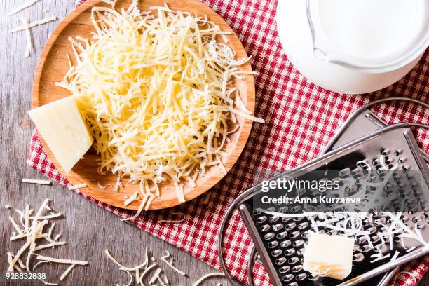 ingredients for pasta dish or pizza - milk, freshly grated parmesan cheese on a wooden table, and kitchen utensils (grater) on a wooden table, top view. messy style. preparations for cooking process. - parmesan cheese pizza stock pictures, royalty-free photos & images
